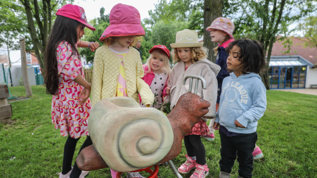 Children in a park look at a snail toy